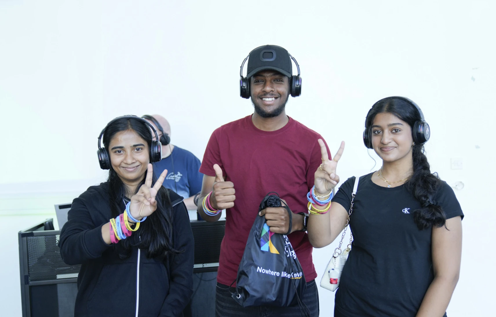 Three students wearing headphones and smiling with peace signs during a silent disco at the Open Day. Three students wearing headphones and smiling with peace signs during a silent disco at the Open Day.